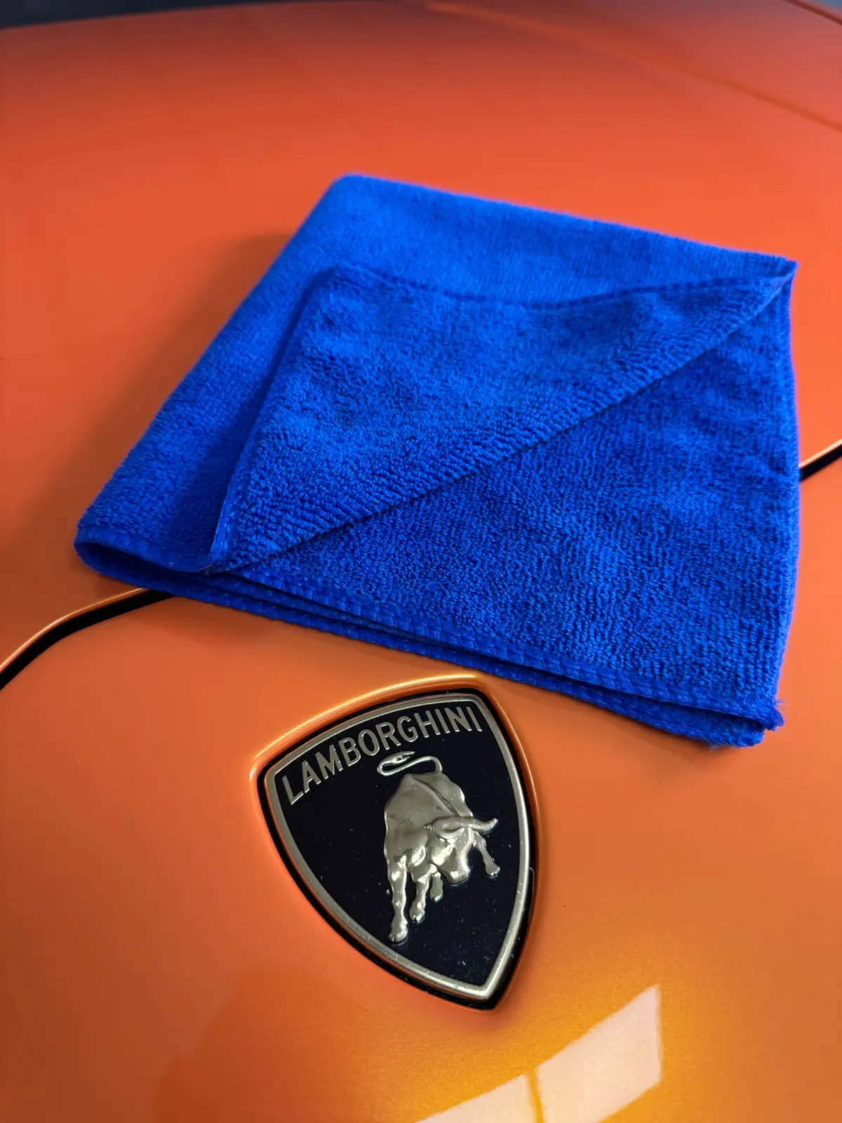 Blue microfibre cloth displayed on orange Lamborghini paintwork